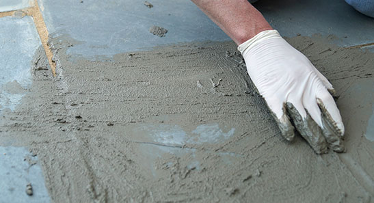 A man is laying cement on the ground